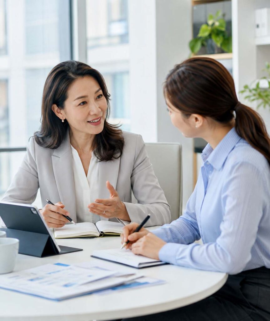 Leader coaching a team member in a bright office during a one-to-one development conversation.